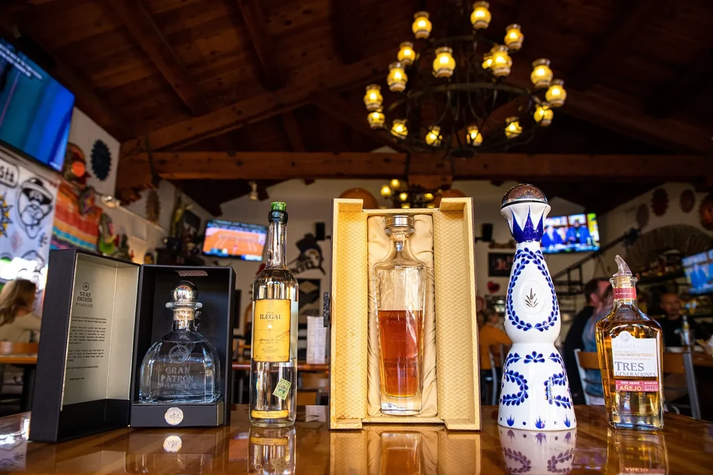 Five premium liquor bottles displayed in a vibrant bar.