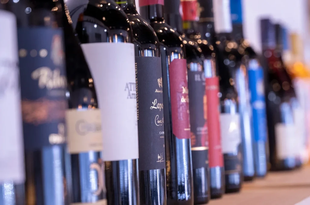 A line of various red wine bottles with distinct labels.