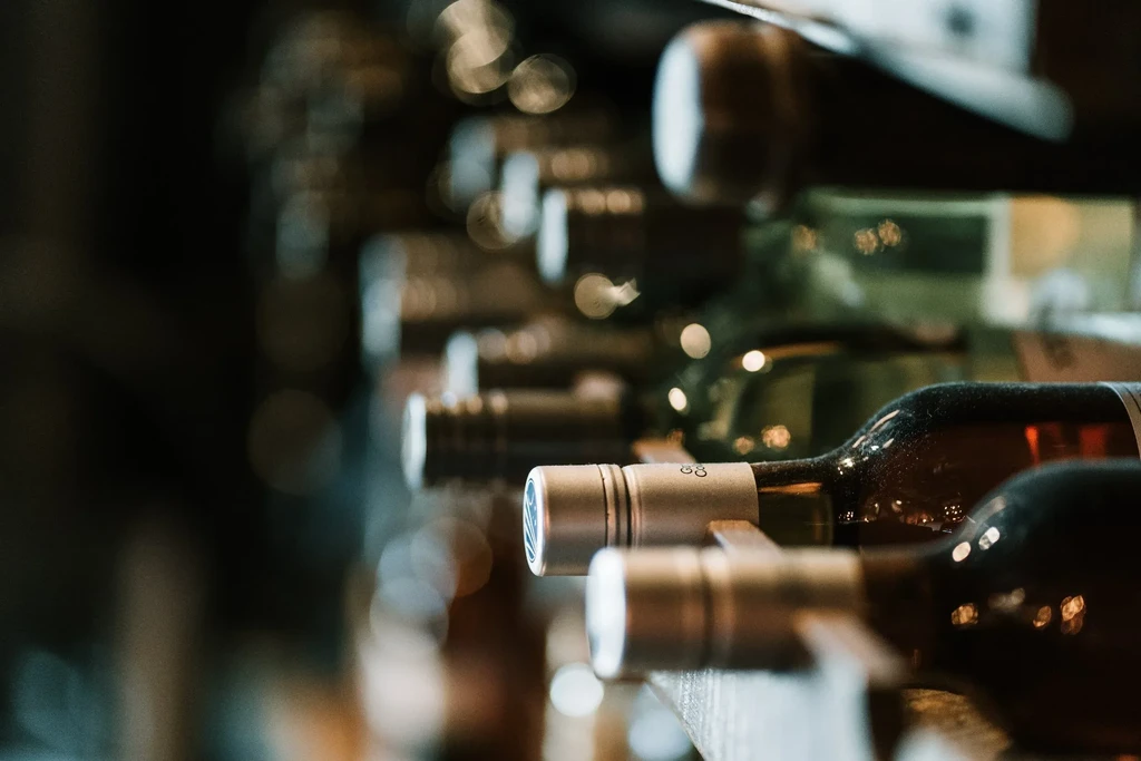 Close-up of red wine bottles horizontally stored in a dim rack.
