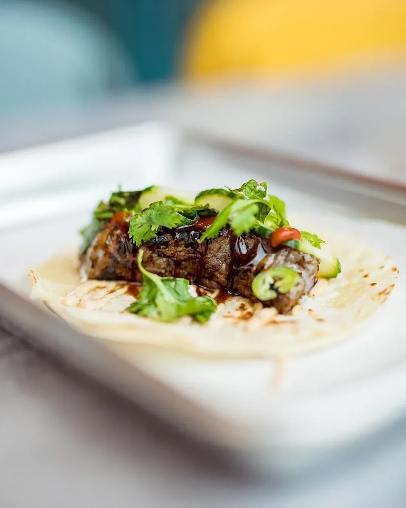 Grilled steak taco topped with cilantro, cucumber, and jalapeño slices.