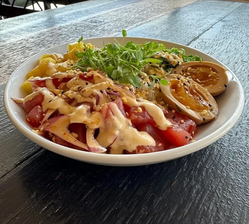 Vibrant tuna poke bowl with mango, microgreens, and soft-boiled eggs.