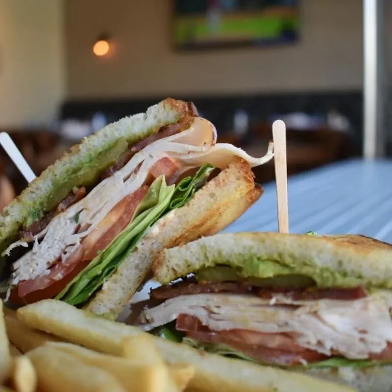 Club sandwich cut in half, skewered, with french fries.
