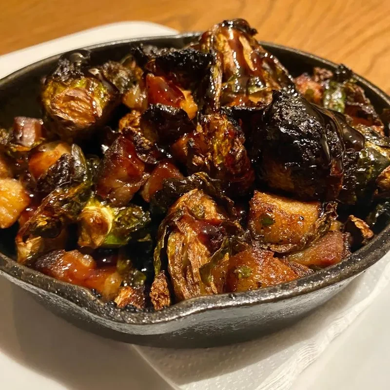 Roasted Brussels sprouts in a cast-iron skillet with a dark glaze.