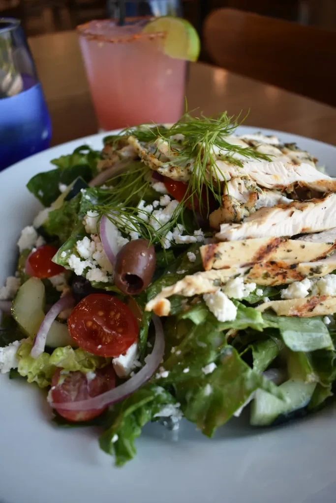 Grilled chicken salad with lettuce, tomatoes, feta, olives, and dill.