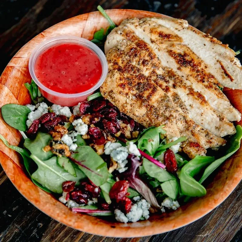 Grilled chicken salad in rustic bowl with blue cheese, cranberries, walnuts.