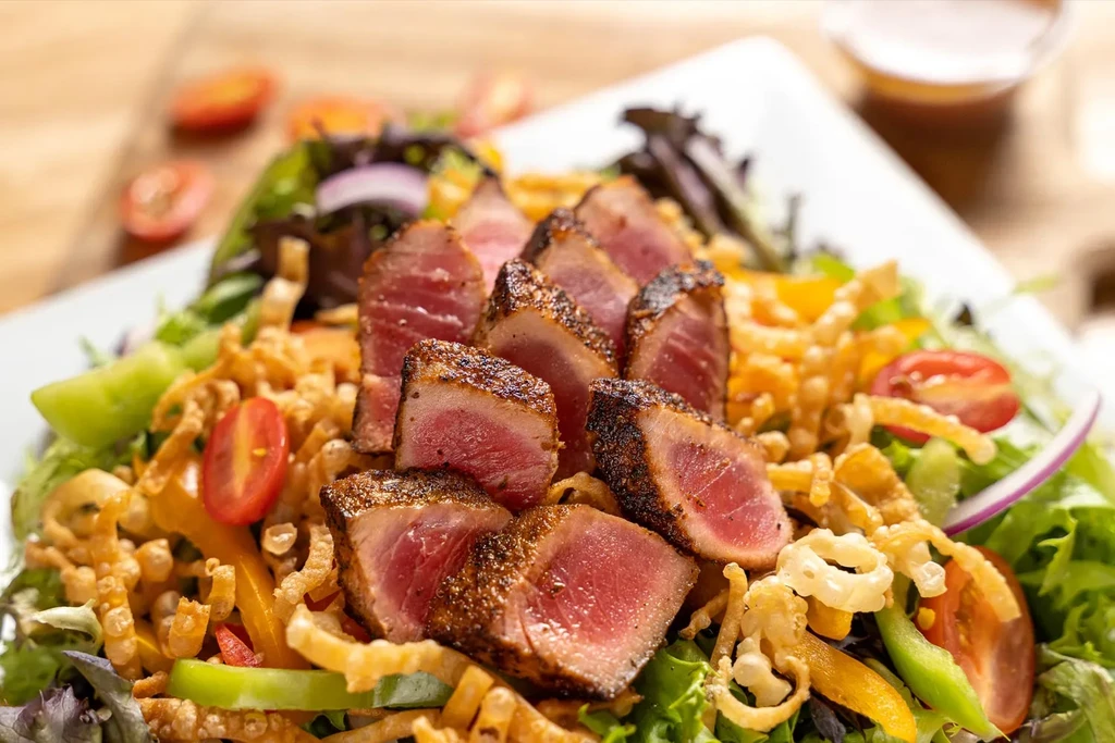Seared tuna salad with mixed greens, tomatoes, peppers, and crispy strips.