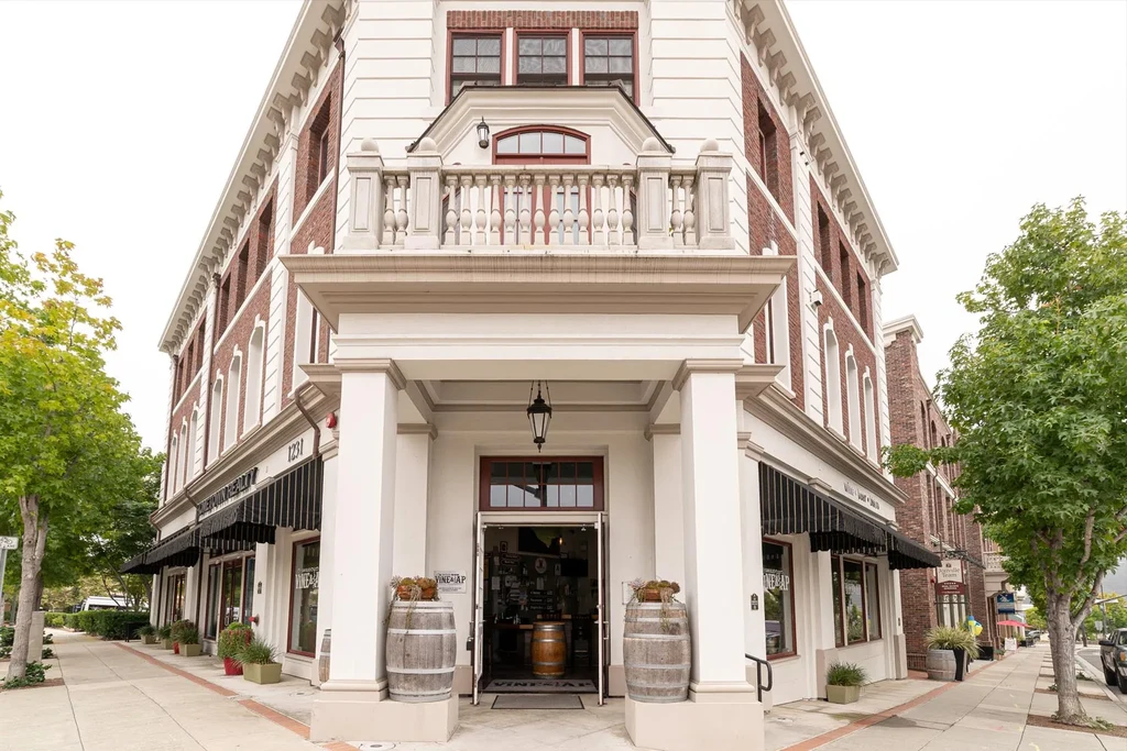 Red brick corner building, 'VINE MAP' restaurant entrance with wine barrels.