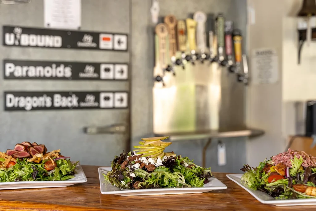 Plated tuna, pear, and pulled pork salads at a brewpub.