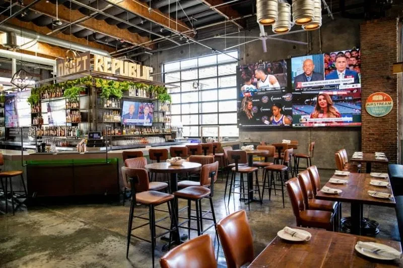 Industrial-chic Draft Republic bar interior with dining area and multi-screen sports display.