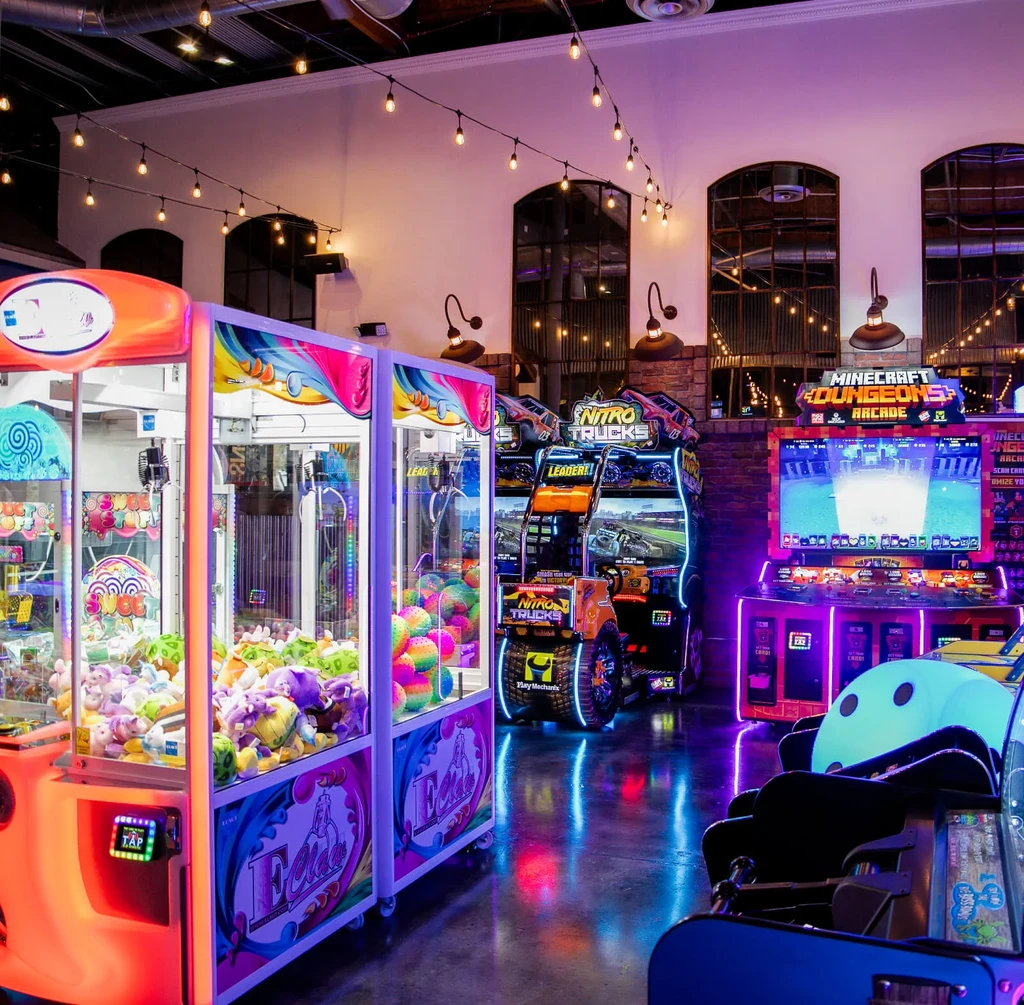 Vibrant indoor arcade with neon-lit machines and plush-filled claw games.