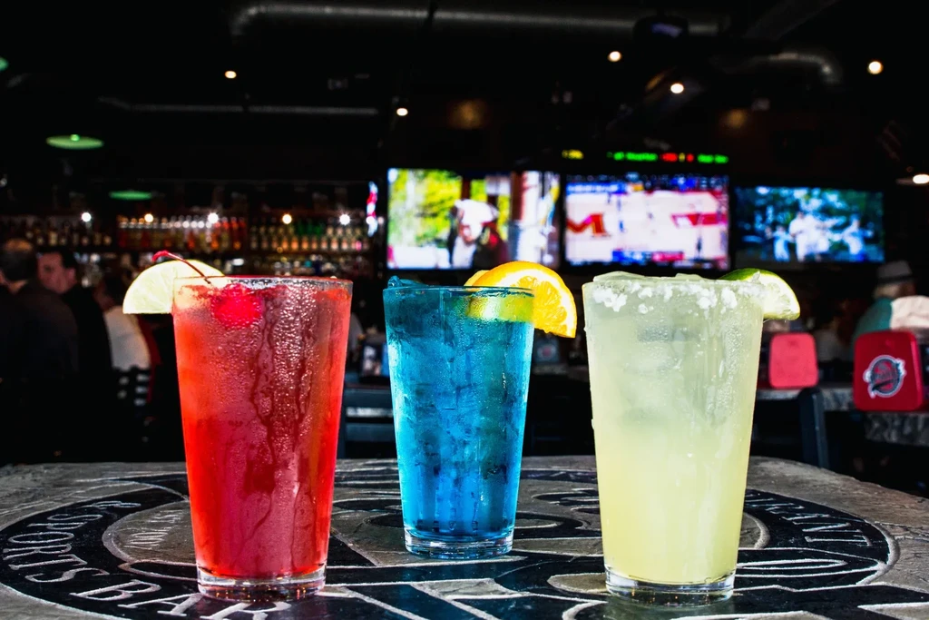 Three colorful, frosty drinks on a sports bar counter.