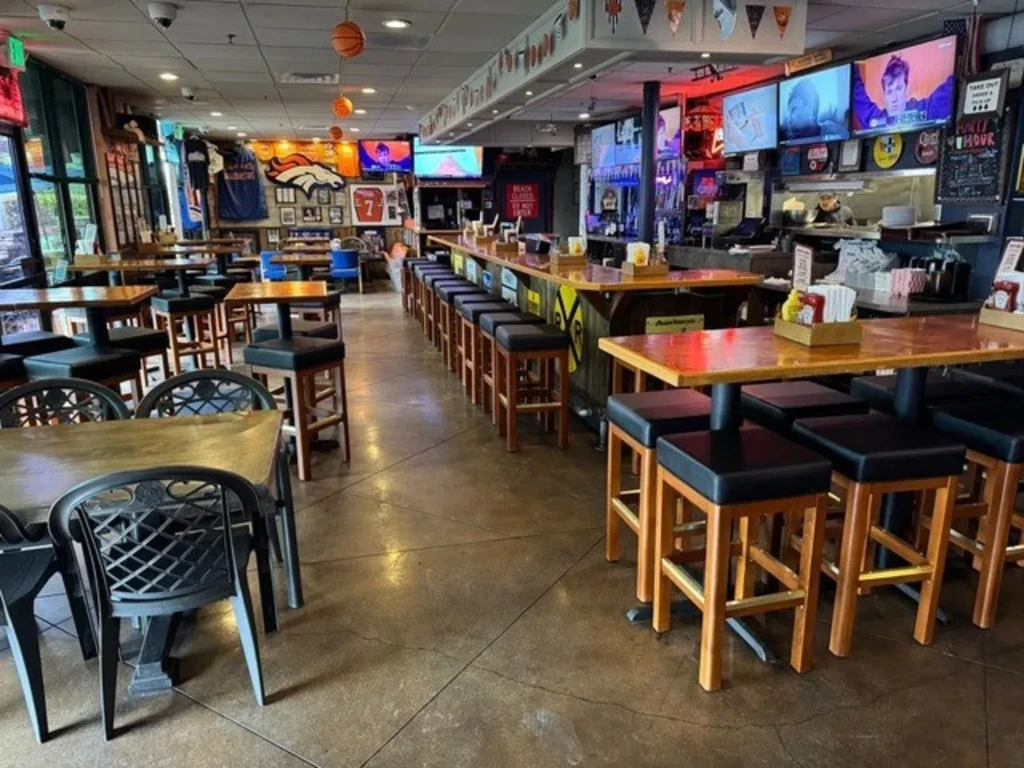 Interior of a bright sports bar with TVs, bar, and memorabilia.