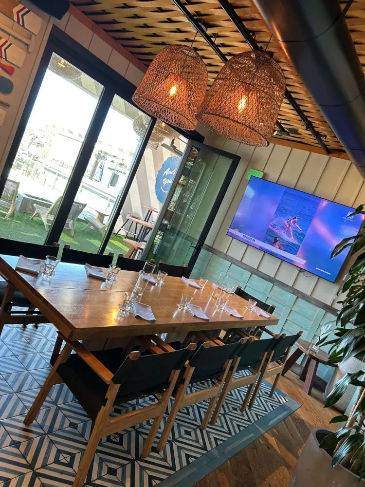 Modern restaurant interior with wooden table, geometric floor, and outdoor patio.