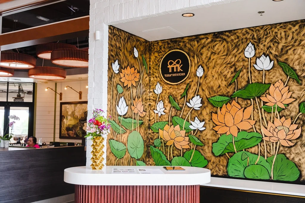 Thai Kitchen entrance with lotus mural and modern white counter.