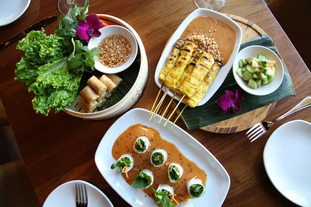 Elegantly presented Thai and Southeast Asian dishes on a wooden table.