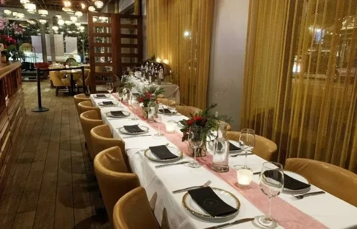 A warmly lit restaurant dining table elegantly set with flowers and candles.