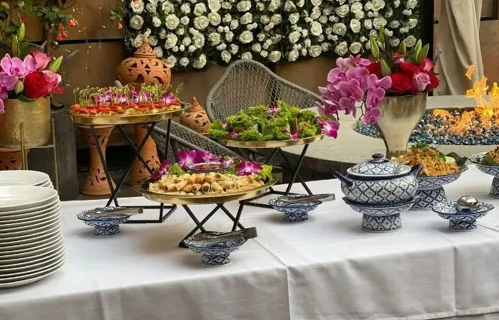 Elegant buffet table with appetizers, salad, flowers, and a fire pit.