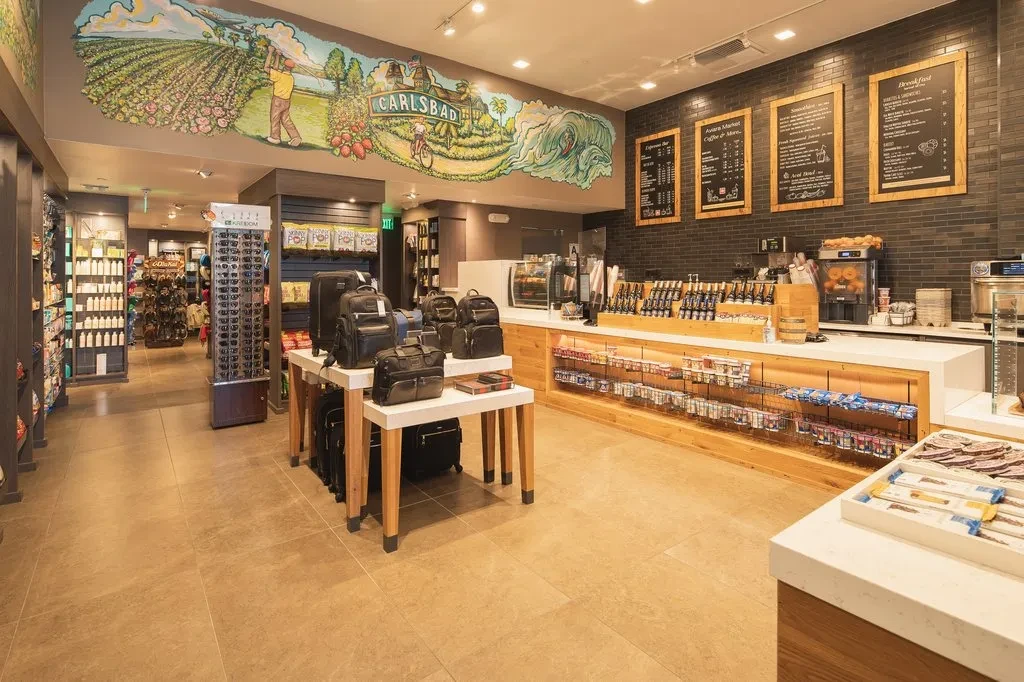 Modern cafe and market interior featuring espresso bar, retail, and Carlsbad mural.