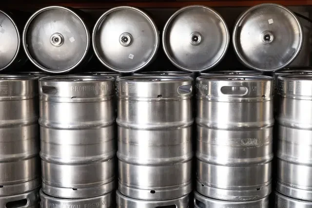 Stainless steel beer kegs stacked, some with 'PROHIBITION BREWING' text.