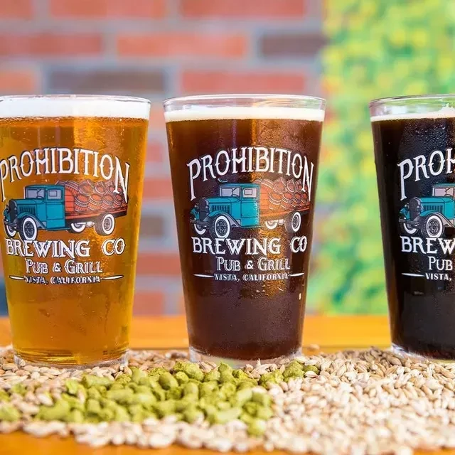 Three Prohibition Brewing beers, grains, and hops on wood.
