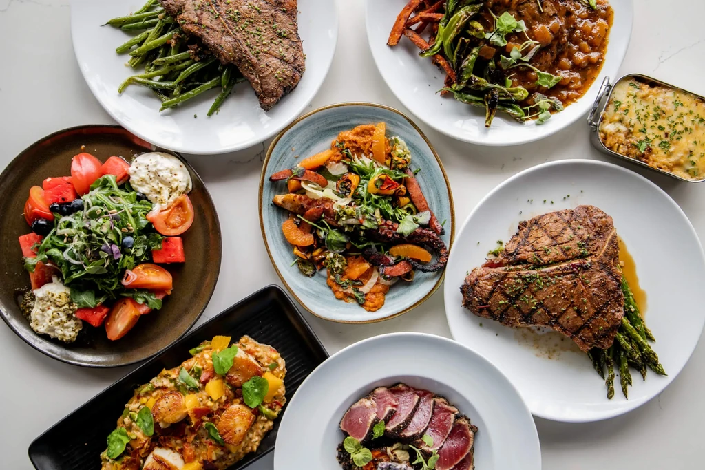 Overhead photograph displaying eight diverse, professionally plated gourmet dishes.