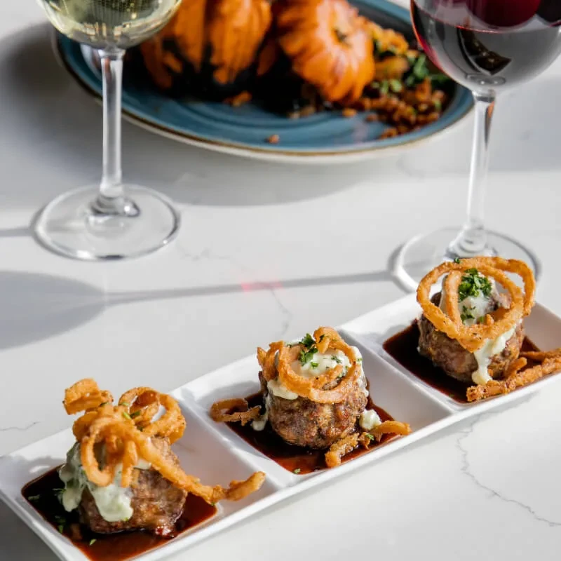 Mini meatloaves with creamy topping, fried onions, herbs, on marble.