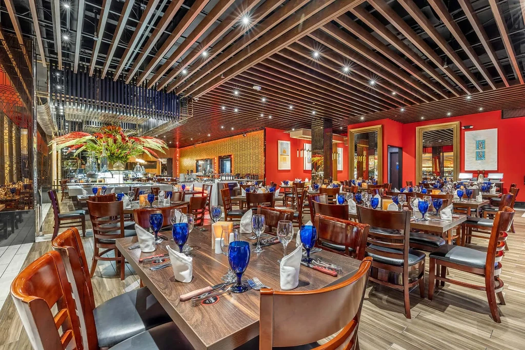 Modern upscale restaurant interior with red walls, ornate mirrors, and wood ceiling.
