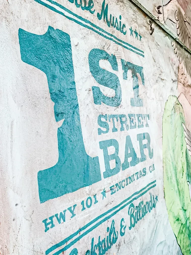 Close-up of a vintage 1st Street Bar sign on a textured wall.