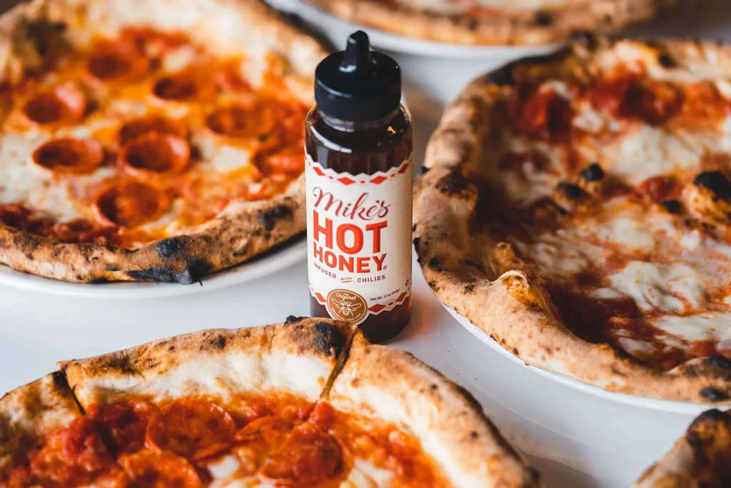 Overhead: Pizzas arranged around a Mike's Hot Honey bottle.