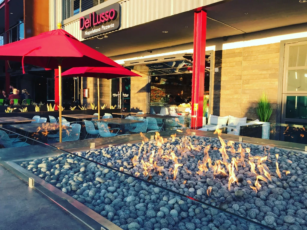 Outdoor patio with a flaming fire pit at Del Lusso Pizzeria.