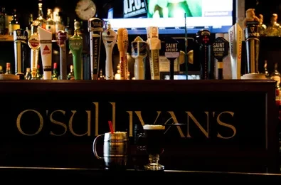 O'Sullivan's bar counter with beer taps and two drinks.