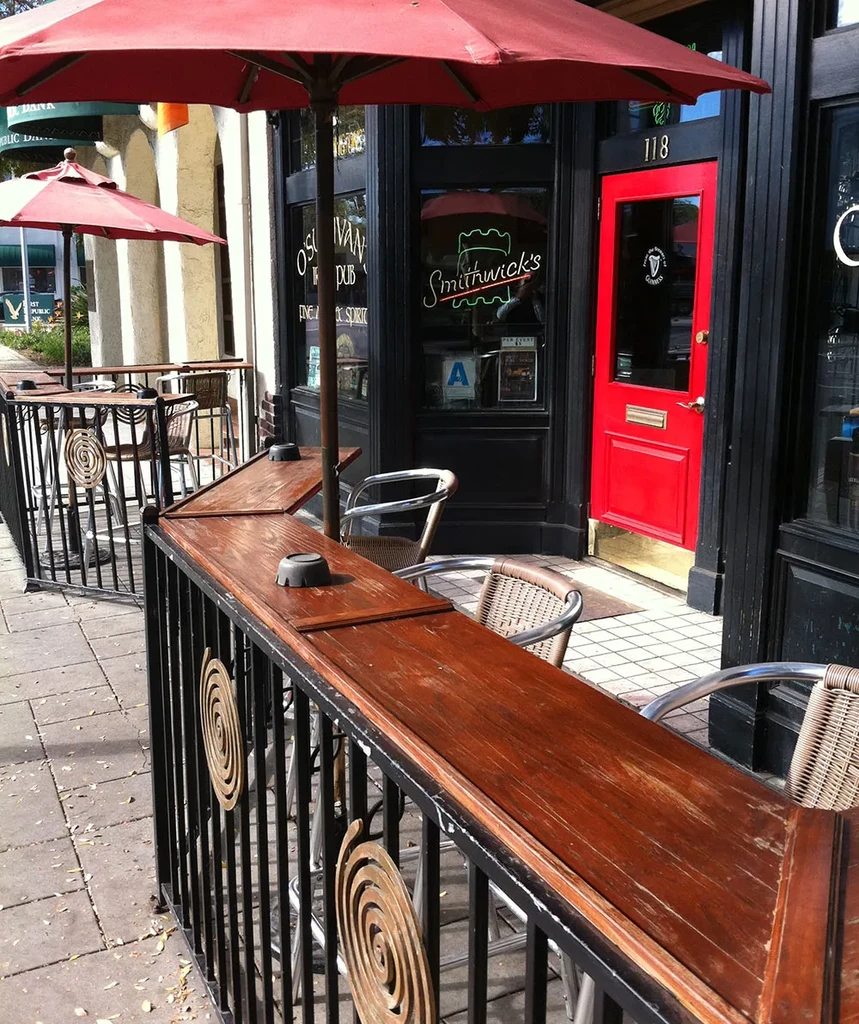 O'Sullivan's Pub facade with red door, street seating, and red umbrellas.