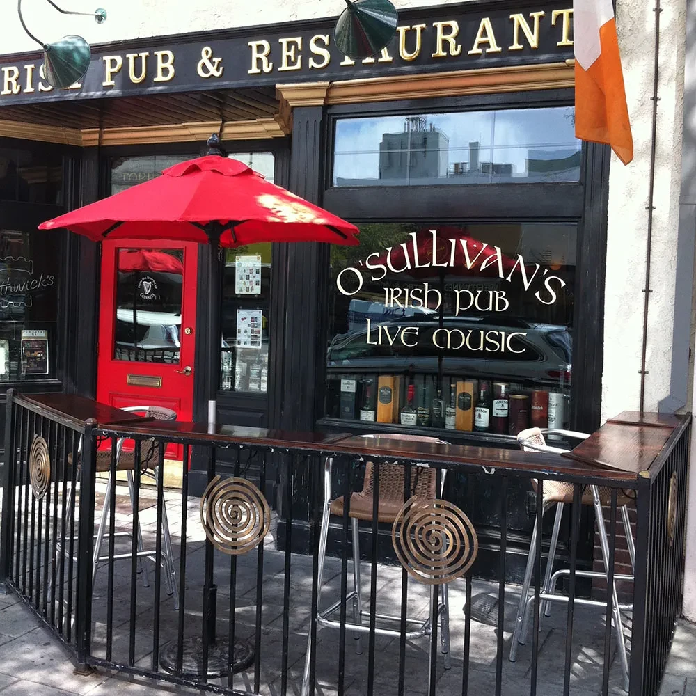 Exterior of O'Sullivan's Irish Pub with red door and outdoor seating.