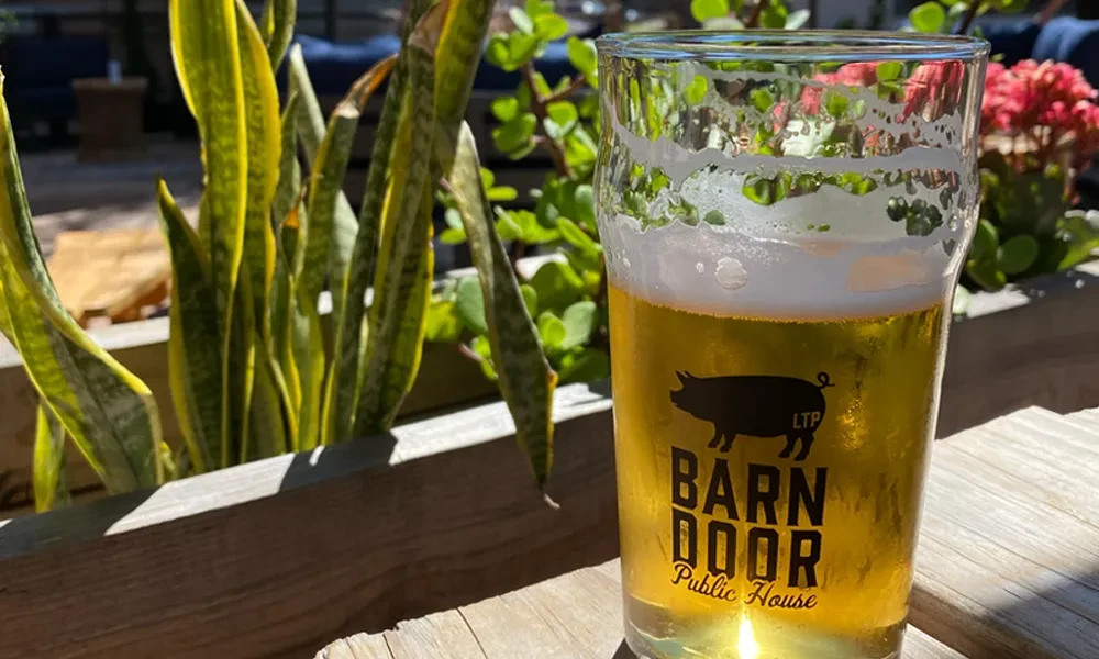 Cold golden beer with a pig logo on a wooden outdoor table.