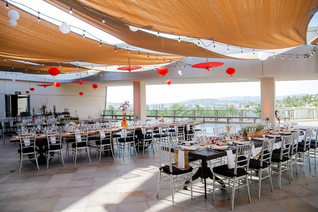 Empty outdoor dining area with Chiavari chairs and Chinese lanterns.