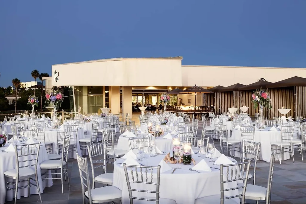 Formal outdoor event setup with white tables, Chiavari chairs, colorful flowers.