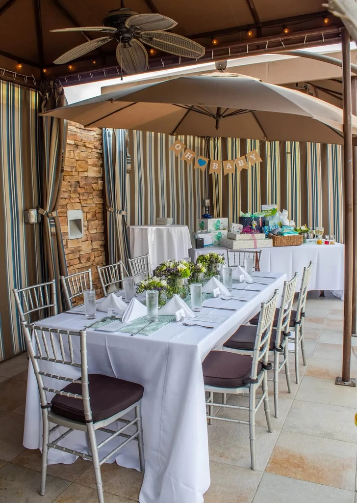 Outdoor baby shower with decorated tables, gifts, and 'OH BABY' banner.