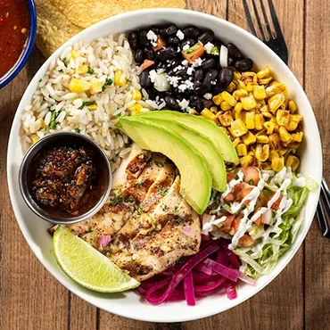 Colorful Mexican chicken bowl with rice, avocado, beans, and pico de gallo.