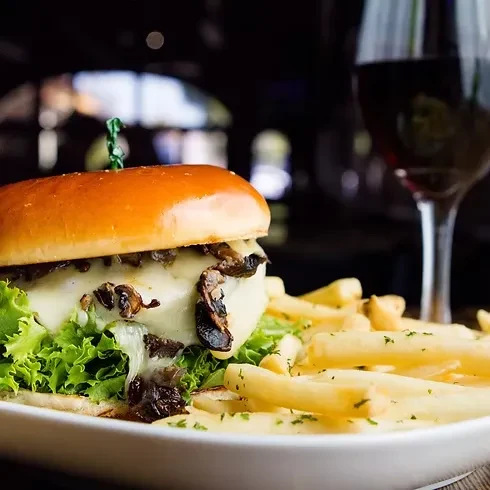 Gourmet burger with melted cheese, mushrooms, and a side of fries.