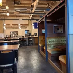Restaurant interior with booth seating, tables, and a bar area.