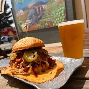 Pulled pork sandwich with jalapeños, cheese crisp, and beer.