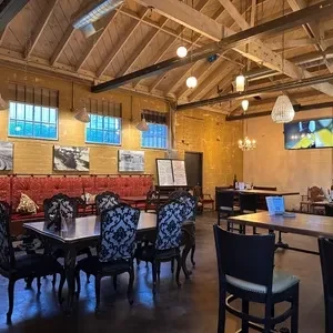 Restaurant interior with exposed beams, brick walls, and various seating.