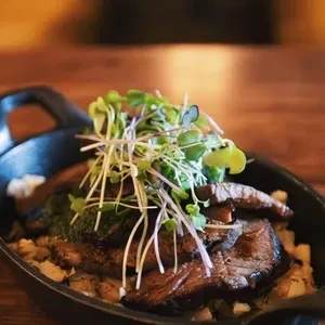 Seared meat with microgreens in a cast-iron skillet.