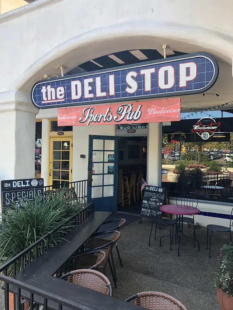The DELI STOP Sports Pub entrance, patio seating, and specials board.