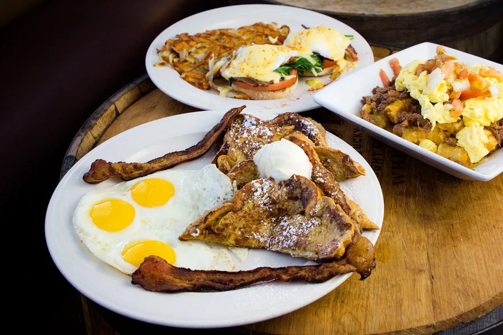 Three diverse breakfast and brunch dishes on a wooden surface.
