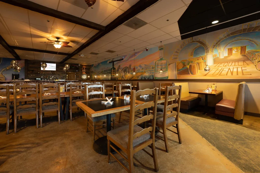 Mexican restaurant interior with tables, booths, and a tequila mural.