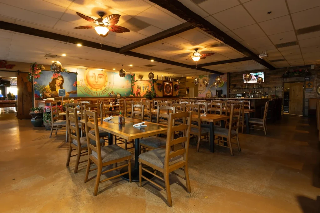 Vibrant restaurant with wooden tables, a bar, and colorful wall murals.