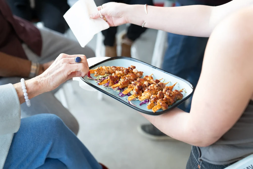 Grilled skewers with cabbage on a blue plate being served.