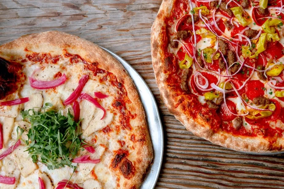 Two pizzas: one white with chicken, one red with pepperoni and sausage.