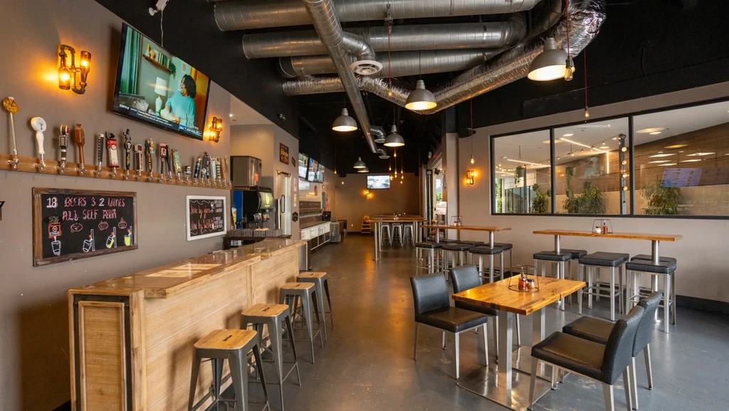 Modern industrial-chic bar interior with self-pour taps and diverse seating.